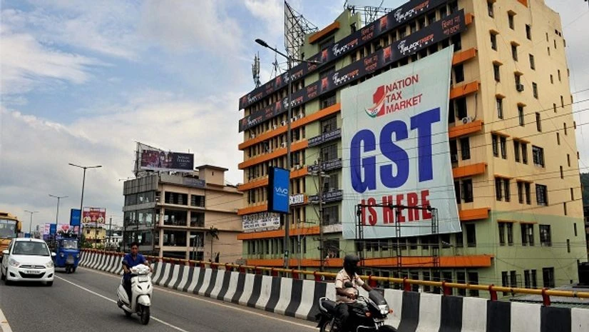 GST Vehicles move past a huge GST poster on the wall of a building, in Guwahati on Friday. Photo: PTI