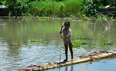 Assam floods: Heavy rains wreak havoc, 13 people dead in Morigaon A girl rows a banana raft in a flood affected area in Assam