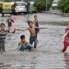 Children enjoy at a water logged street after heavy rains in New Delhi on Monday. Photo: PTI