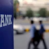 Commuters walk past a bank sign along a road in New Delhi. (Photo: Reuters)