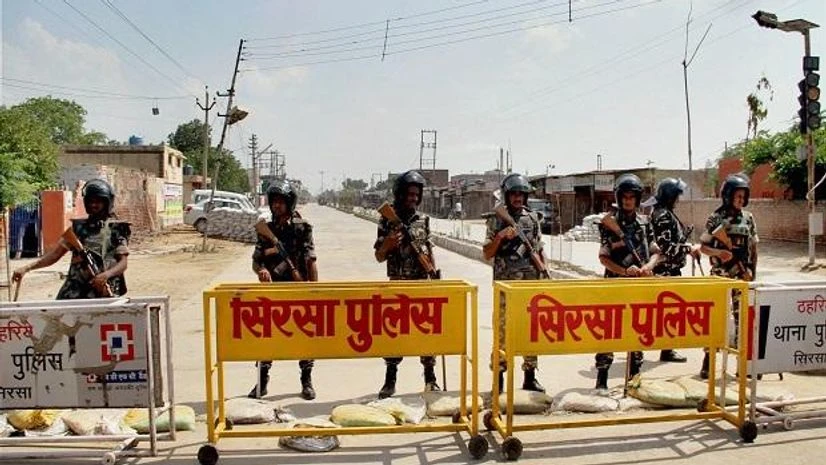 Dera Sacha Sauda search Sirsa: Security forces stand guard at the main entrance to the Dera Sacha Sauda headquarters, in Sirsa district of Haryana on Friday, ahead of the search operations inside the premises. PTI Photo