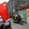 A rag-and-bone man rides towards a hutong alley decorated with Chinese national flags during the ongoing 19th National Congress of the Communist Party of China, in Beijing