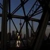 A man walks on a bridge in front of the financial district of Pudong in Shanghai, China