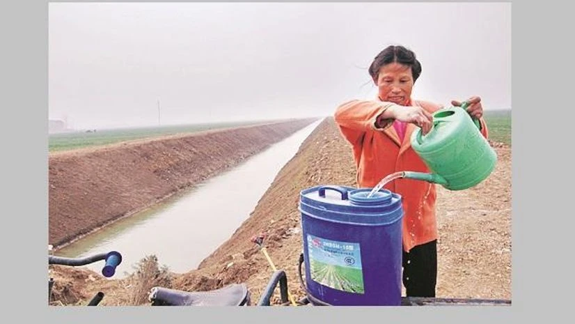 Chinese woman pours water into her container near a newly dug aqueduct in Xiangfan Chinese woman pours water into her container near a newly dug aqueduct in Xiangfan