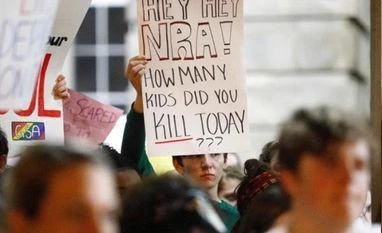 Ties to National Rifle Association leave companies scrambling for cover A student holds a sign addressing the National Rifle Association during a demonstration calling for safer gun laws outside the North Carolina State Capitol building.