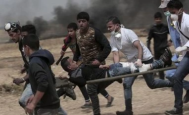 More Jerusalem clashes on eve of contentious Israeli parade Palestinian protesters evacuate a wounded youth during clashes with Israeli troops along Gaza's border with Israel, east of Khan Younis, Gaza Strip, on Friday. | Photo: AP/PTI