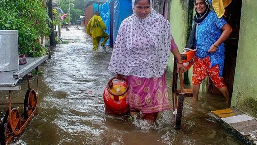 rains, waterlogging, mumbai A woman carries at LPG cylinder in a flooded locality after heavy rains, in Kalyan, Mumbai on Saturday