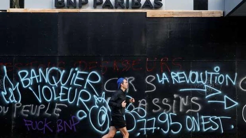 Paris riot, emmanuel macron A man jogs past a vandalized bank front the morning after clashes with protesters wearing yellow vests, a symbol of a French drivers' protest against higher diesel fuel taxes, in Paris, France