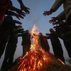 People keep themselves warm around a bonfire during a cold winter morning on the outskirts of Jammu