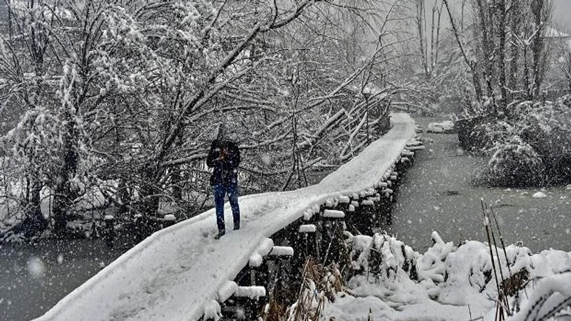 A man walks on a snow-covered wooden bridge during heavy snowfall, in Srinagar A man walks on a snow-covered wooden bridge during heavy snowfall, in Srinagar