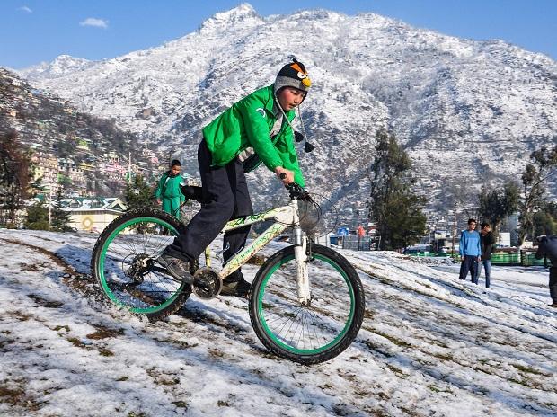 A cyclist rides across melting snow field, in Kullu A cyclist rides across melting snow field, in Kullu