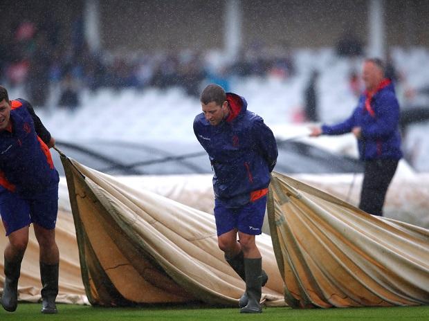 Groundstaff put covers on the pitch as rain delays play Groundstaff put covers on the pitch as rain delays play