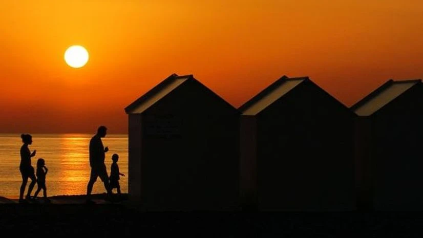 People walk beside beach cabins on a pebbled beach, during sunset as a heatwave hits France, in Cayeux-sur-Mer. Photo: Reuters People walk beside beach cabins on a pebbled beach, during sunset as a heatwave hits France, in Cayeux-sur-Mer. Photo: Reuters