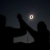 People react while observing a solar eclipse at Incahuasi, Chile
