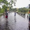 People wade theough the flooded national highway closed after heavy rains, at Bagori Range in Kaziranga National Park