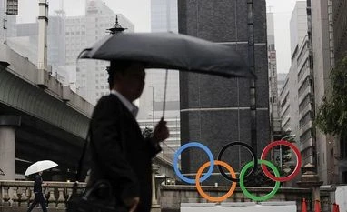 Tokyo 2020 sponsor Toyota 'conflicted' over Olympics as Covid cases surge Commuters walk past the Olympic Rings in Tokyo | AP photo