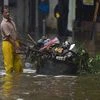 A BMC worker carries a garbage cart across a waterlogged street after heavy rain, at Sion in Mumbai