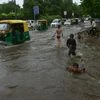 Children play while vehile ply at a waterlogged road after rains, in New Delhi