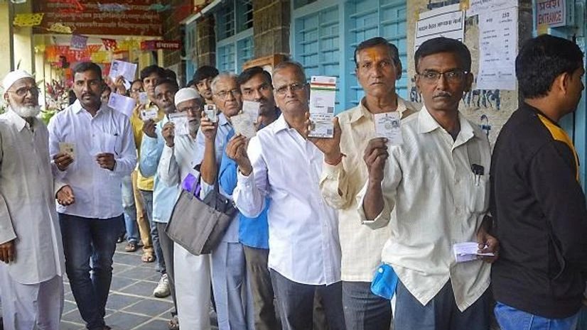 maharashtra elections Voters stand in a queue and show their voting cards as they wait to cast their votes at a polling station for the Maharashtra Assembly elections, in Karad, Monday, Oct. 21, 2019
