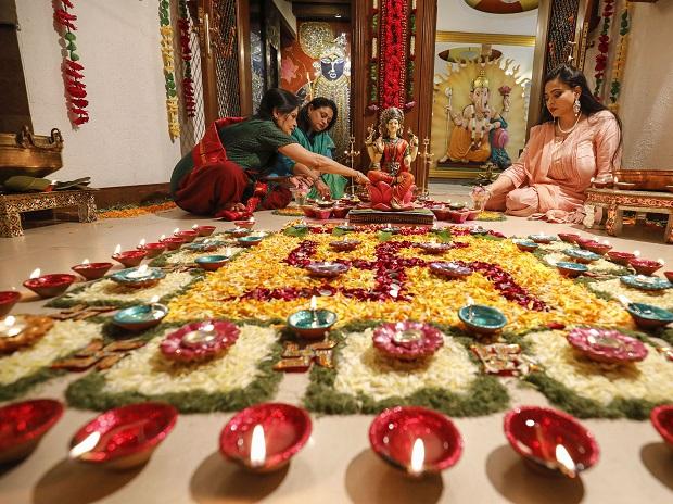 Women arrange oil lamps and flowers around a rangoli Women arrange oil lamps and flowers around a rangoli