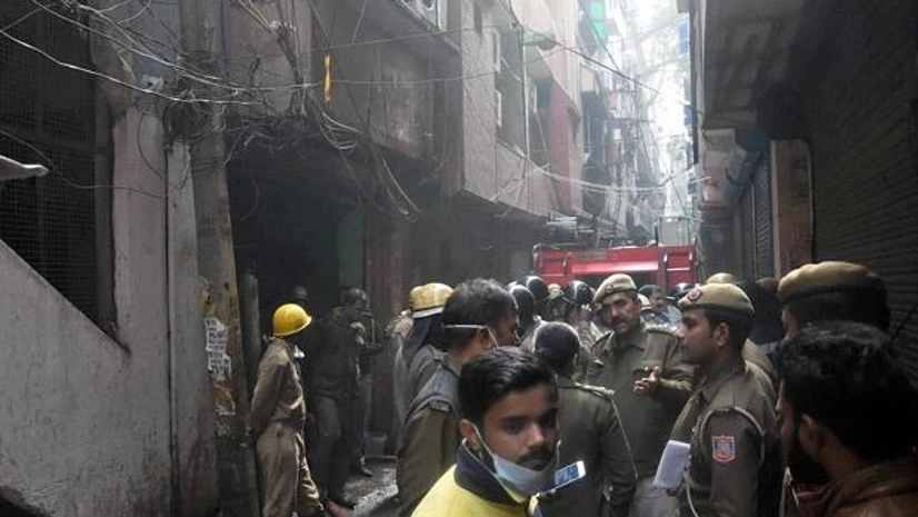 Rani Jhansi Road, Delhi Anaj Mandi fire, Anaj Mandi fire Police personnel and onlookers stand near a factory at Rani Jhansi Road where a major fire broke out in New Delhi. Photo: PTI