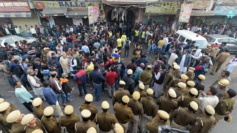 Rani Jhansi Road, Delhi Anaj Mandi fire, Anaj Mandi fire Police personnel and onlookers stand near a factory at Rani Jhansi Road where a major fire broke out in New Delhi. Photo: PTI