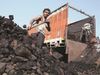 A coal mine labourer loading coal inside a truck.