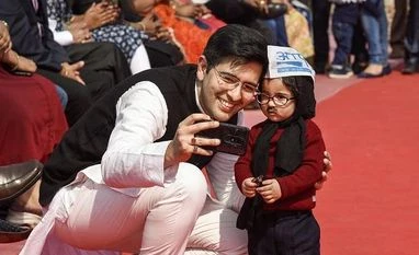 aap, delhi elections, delhi election results, app workers AAP MLA Raghav Chadha with a 'chotu mufflerman' during Delhi CmArvind Kejriwal's swearing-in ceremony at Ramlila Maidan in New Delhi. (Photo: PTI)
