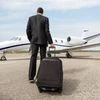 Rear view of businessman with luggage walking towards corporate jet