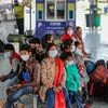 Passengers wearing protective face masks wait at a railway station following cancellation of trains in the wake of coronavirus pandemic in Jammu