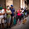 People line up to buy food, some wearing protective masks as a precaution against the spread of the new coronavirus, in Havana, Cuba. Photo: PTI
