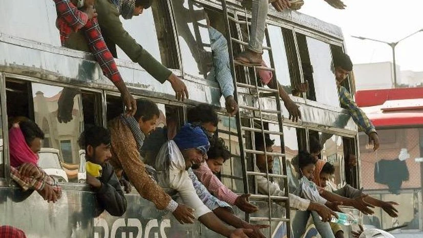 coronavirus, migrant workers Migrant workers try to reach out for food packets being distributed by volunteers as they leave in an overloaded bus to their respective destinations, during the nationwide lockdown in wake of the coronavirus pandemic, in Patna. Photo: PTI