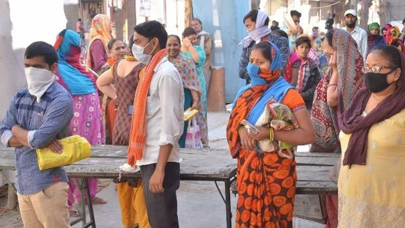 lockdown, coronavirus People stand in a queue to buy milk at a shop during a nationwide lockdown in the wake of coronavirus pandemic, in Mathura
