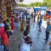 People maintain social distancing while standing in queues to buy essential items from shops at APMC market, during ongoing COVID-19 lockdown, in Navi Mumbai