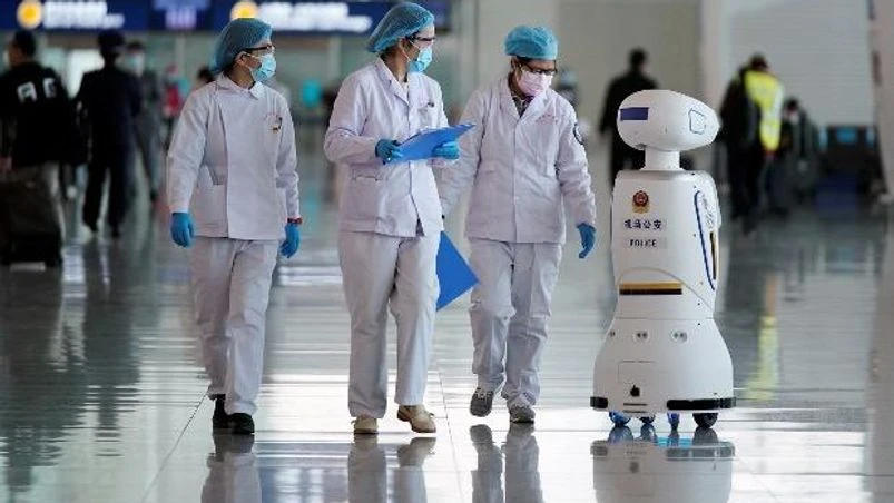 coronavirus, China Medical workers walk by a police robot at the Wuhan Tianhe International Airport. Photo: Reuters