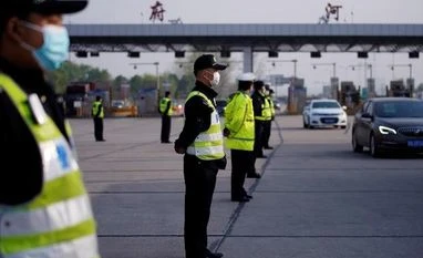 Coronavirus 2.0? China may test all 11 mn Wuhan residents in next 10 days Police officers stand guard at a toll station of an expressway. Photo: Reuters