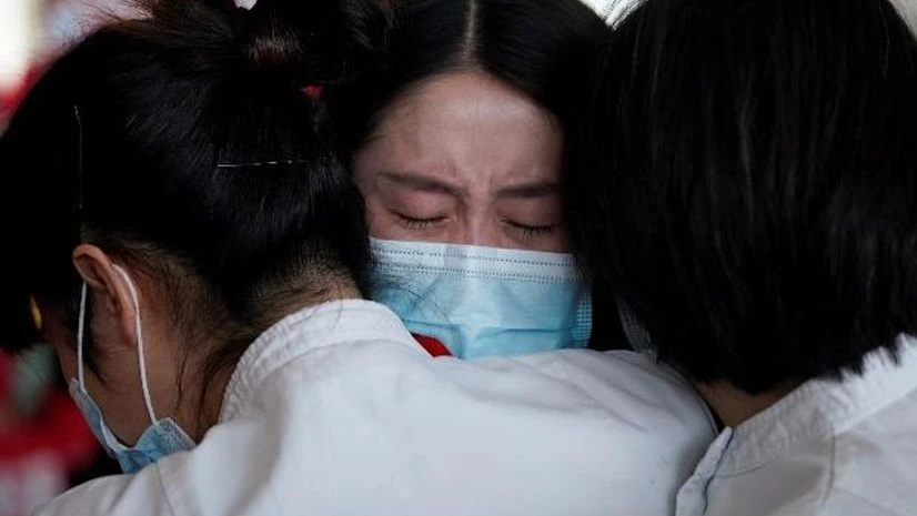 Medical workers hug at the Wuhan Tianhe International Airport after travel restrictions to leave Wuhan were lifted. File Photo: Reuters Medical workers hug at the Wuhan Tianhe International Airport after travel restrictions to leave Wuhan were lifted. File Photo: Reuters