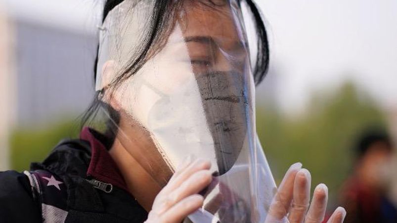 coronavirus, China A traveller adjusts her face shield outside Hankou Railway Station. Photo: Reuters