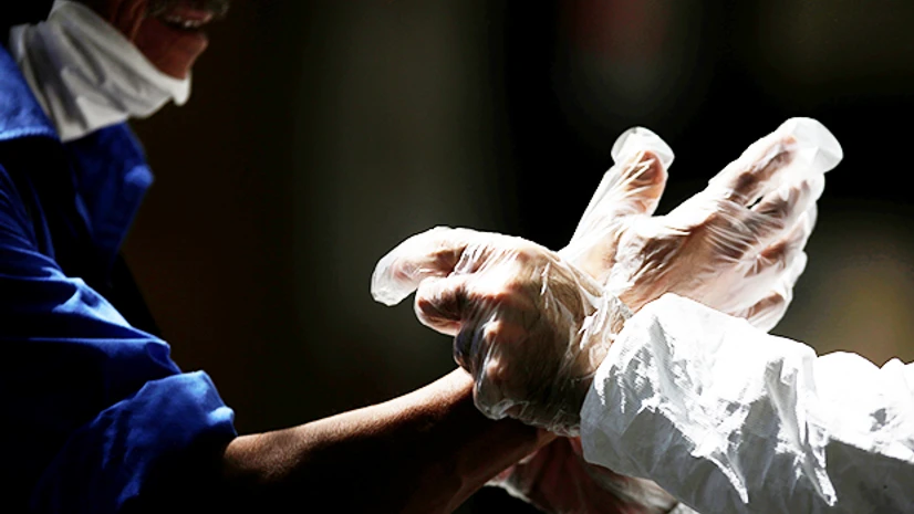 protective gears, protective gloves, coronavirus An activist wearing protective suit helps a pedestrian to put on gloves, during an awareness campaign, amid the spread of the coronavirus disease. Photo: Reuters