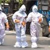 Health workers wearing protective suits walk on a street during their door-to-door survey to detect COVID-19 positive cases amid a nationwide lockdown to curb the spread of coronavirus, in Kolkata