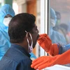 Medics wearing protective suits collect swab samples for Covid-19 test of vegetable vendors, who had shops in Vadasery bus stand, in Kanyakumari District. Photo: PTI