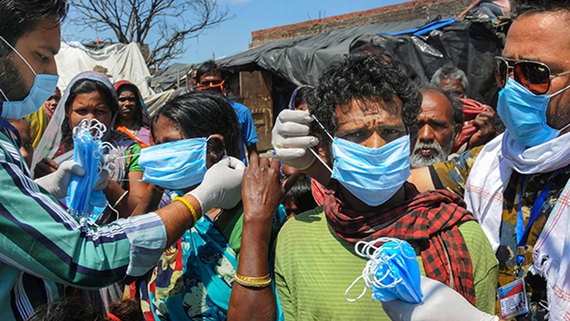 Slum dwellers, coronavirus, Covid-19 protective masks Slum dwellers, oblivious of social distancing guidelines, queue up to receive face masks from the members of the National Human Rights and Crime Control Organization during ongoing COVID-19 lockdown, in Amritsar. Photo PTI