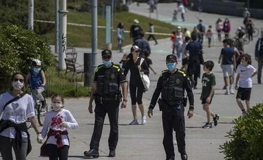 Catalan police officers patrol as families with their children walk along a boulevard in Barcelona, Spain, Sunday, April 26, 2020 as the lockdown to combat the spread of coronavirus continues | Photo: AP/PTI coronavirus