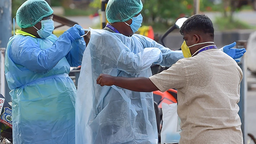 Coronavirus, lockdown Civil defence officials wear protective suits to help a man who was lying on the roadside near Hebbal flyover during a nationwide lockdown imposed in the wake of novel coronavirus pandemic, in Bengaluru. Photo: PTI