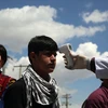 A health worker checks the temperature of car passengers in an effort to help prevent the spread of the coronavirus, as they enter the city in the Paghman district of Kabul, Afghanistan. Photo: PTI