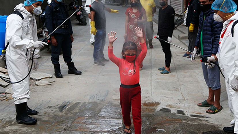coronavirus, Nepal, Covid-19 A young Nepalese girl is sprayed with disinfectants as she arrives to get free food distributed by social workers during lockdown. Photo: PTI