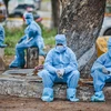 Corporation workers in protective suits wait outside a hospital to get the test reports of a deceased, during the lockdown in Vijayawada. Photo: PTI