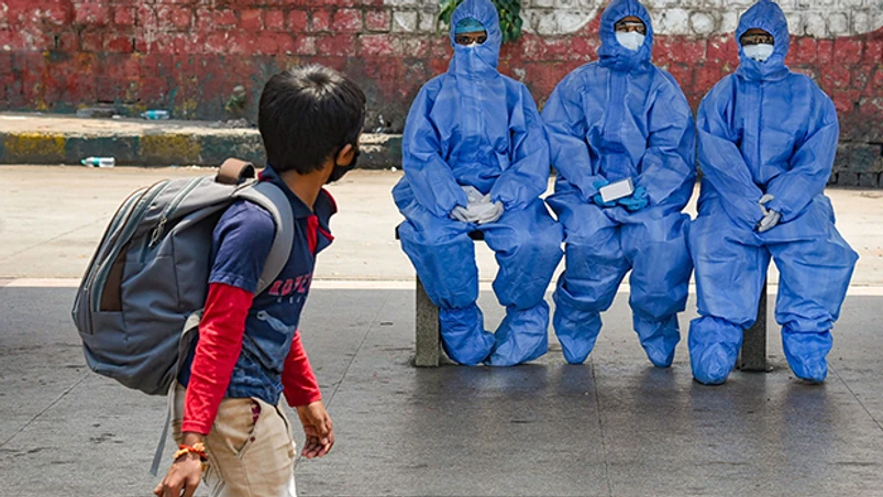 Lockdown 3.0, coronavirus, Covid-19, medics A young boy walks past medics waiting to check the temperature of passengers at Majestic bus stand in Bengaluru. Photo: PTI