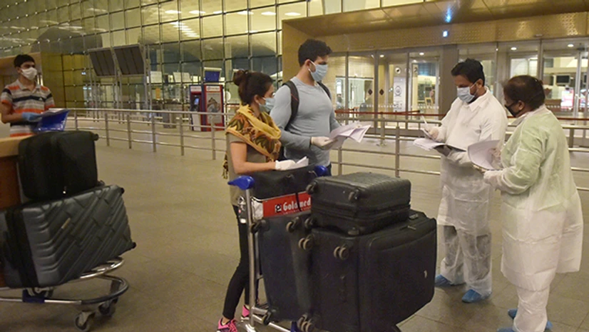 India's mass evacuation, Vande Bharat Mission, special Air India flights, Indians stranded abroad, Coronavirus, Covid-19, Bahrain, UAE, USA, Malaysia, Kuwait, Singapore, London, airport Airport staff in protective suits check passengers as they arrive to board the special Air India flight for London, from Mumbai Airport Terminal 2. Photo: PTI