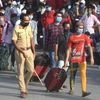 A police constable controls migrants to avoid stampede like situation outside Dharavi slums as they wait to take buses to reach a railway station and board a special train to their native places